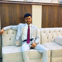 Jamel Alshalabe, sitting on a white sofa in a light grey suit